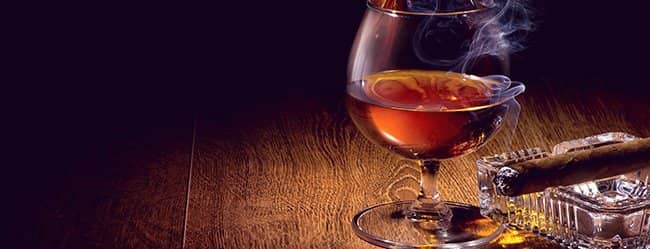 Glas Whisky und Zigarre auf dem Tisch als Symbol für Männlichkeit