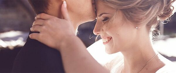 Bräutigam küsst Braut auf die Stirn als Symbolbild für die Vorstellungen beim Heiraten