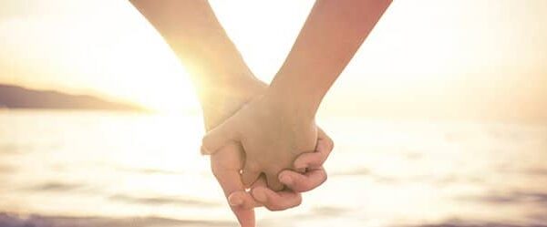 Zwei Menschen halten Händchen als Symbol für karmische Liebe